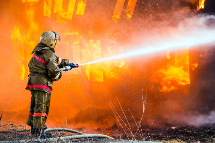 un bombero combate un incendio con su manguera