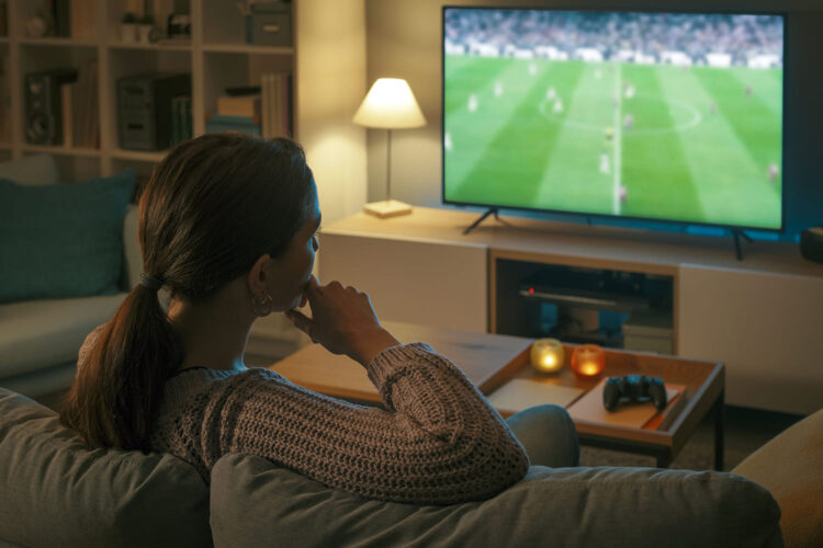 una mujer ve un partido de fútbol en el salón de su casa