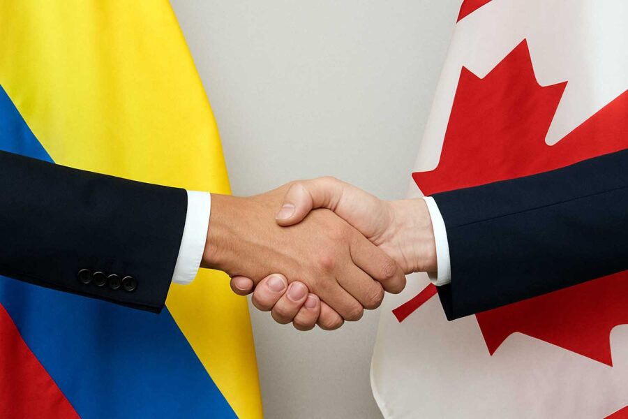 dos hombres se estrechan la mano con las banderas de Colombia y Canadá al fondo