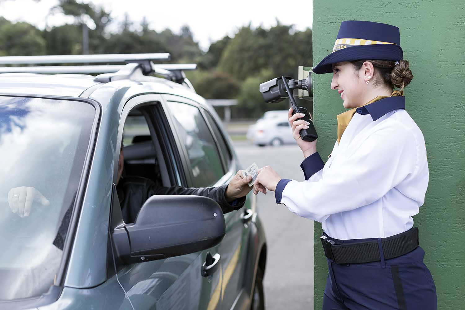 una mujer guarda de seguridad comprueba la documentación de un visitante en un control de acceso
