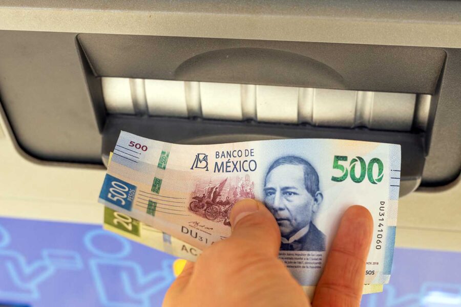 una persona saca pesos mexicanos en un cajero automático